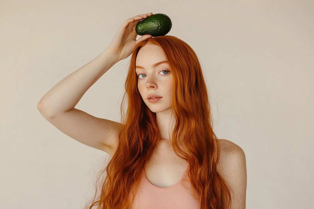 Frau mit langen gesunden Haaren hält Avocado über ihrem Kopf