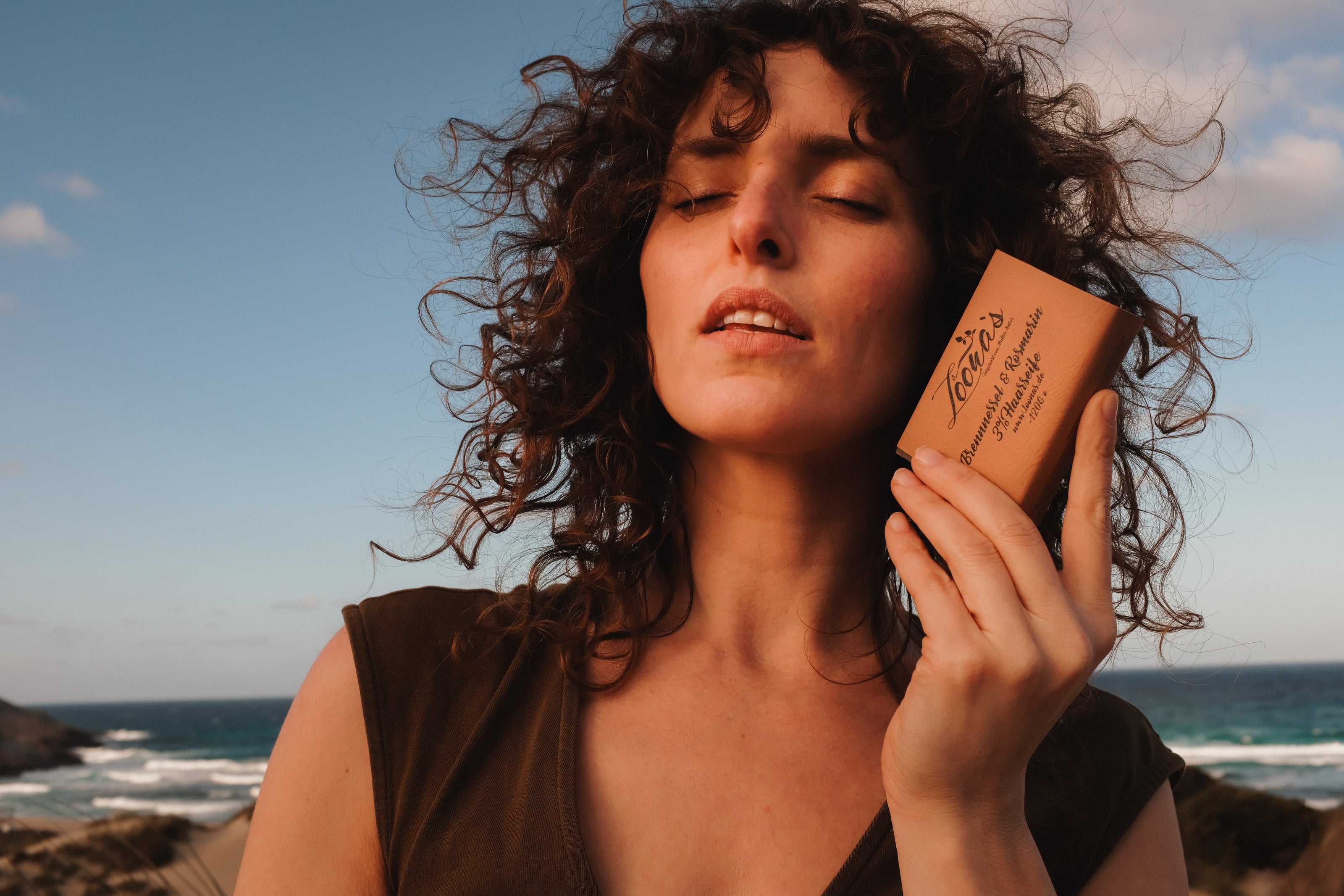 Frau mit Haarseife und Naturlocken am Strand